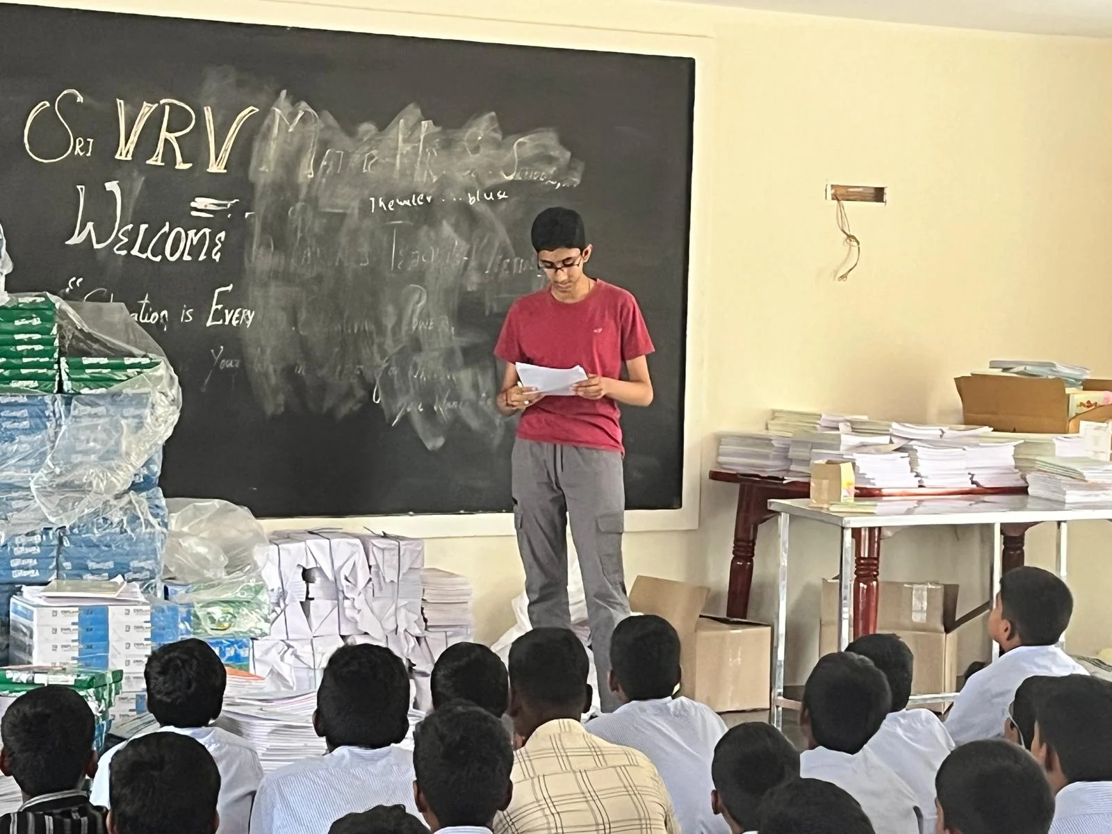 A lesson at the front of a classroom, with students seated facing the blackboard.