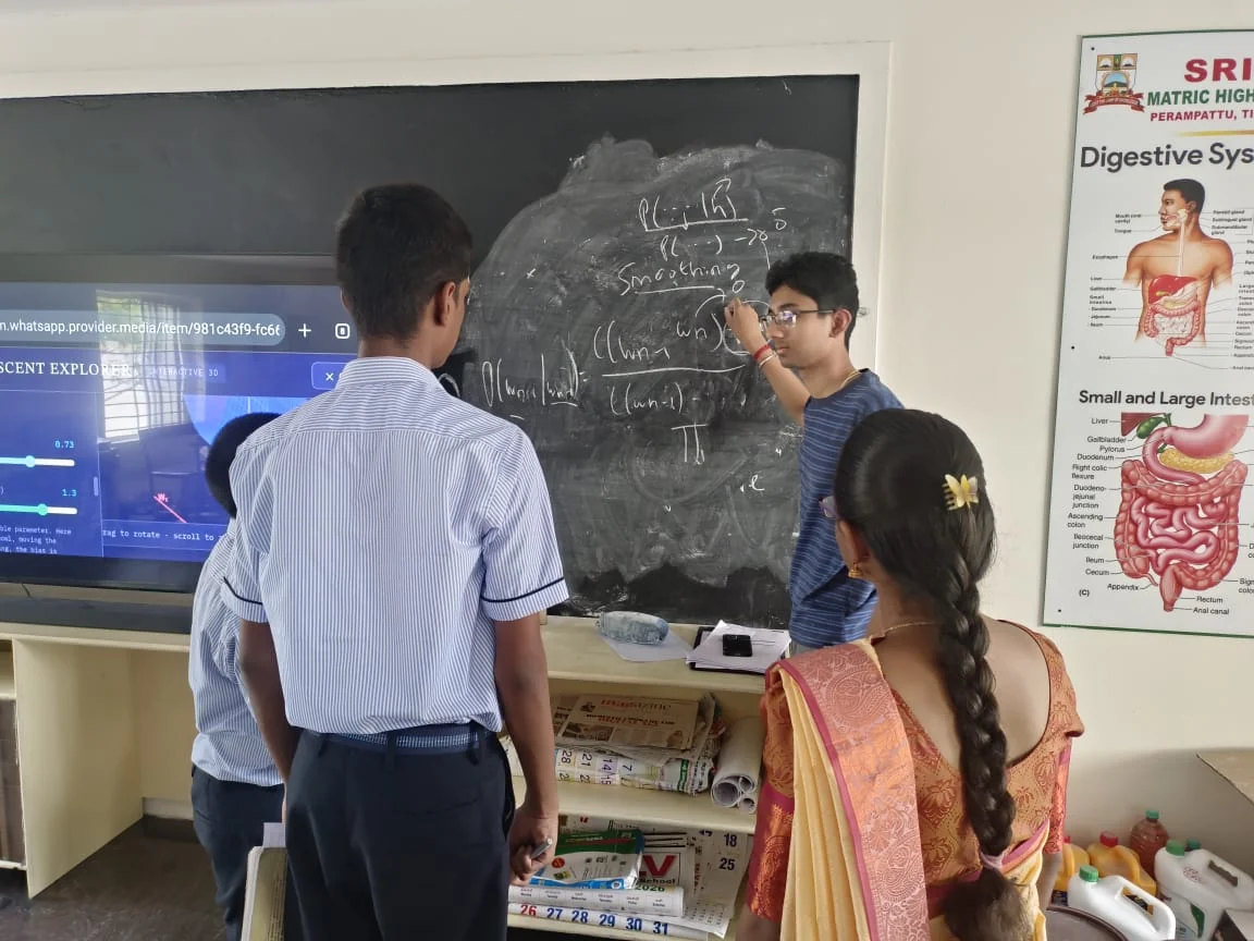 Discussing a model with students beside the blackboard.